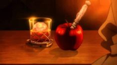 an apple with a knife sticking out of it sitting on a table next to a candle