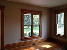 an empty room with two windows and hard wood flooring on the other side of the room