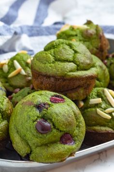 some green colored pastries with almonds and pistachio toppings on a plate