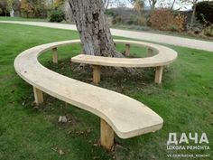 two wooden benches sitting next to a tree in the grass near a path and walkway