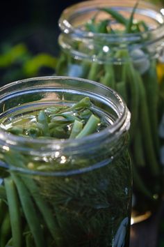 three jars filled with green beans on top of a table