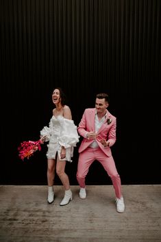 two people dressed in pink and white posing for a photo together with flowers on the floor