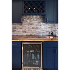 a wine cooler in the middle of a kitchen with blue cabinets and counter top space