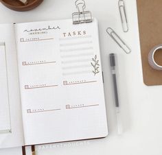 an open planner book sitting on top of a desk next to a cup of coffee