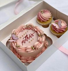 two cupcakes with pink frosting in a box