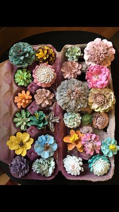 there are many small flowers in the tray on the table top, and one is made out of clay