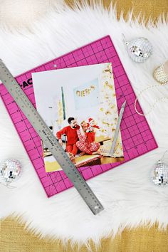 a pink photo frame sitting on top of a white fur covered floor next to a ruler