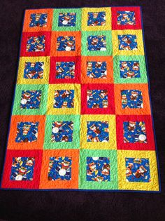 a multicolored quilt is laying on the floor in front of a black background