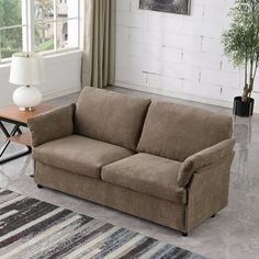 a living room with a brown couch and rugs on the floor in front of a white brick wall