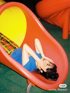 a woman laying on top of a red chair