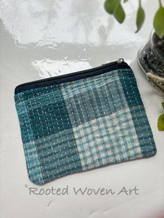 a blue and white checkered purse next to a potted plant