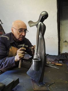 an older man is working on a sculpture