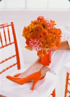 a woman is sitting on a chair with her legs crossed and holding a bouquet of flowers