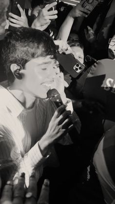 a young man holding a microphone surrounded by people