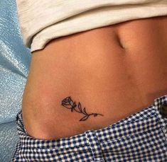 a woman's stomach with a small flower tattoo on her side ribcage