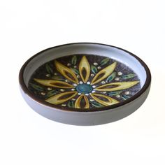 a white bowl with yellow and green designs on it