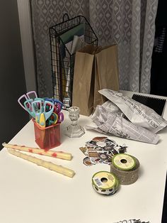 the table is covered with craft supplies and paper bags, scissors, tape, markers, and other items