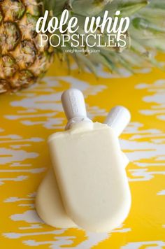 pineapple popsicles sitting next to a pineapple on a yellow and white tablecloth