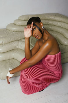 a woman sitting on the floor in front of a pile of pillows with her hands to her face