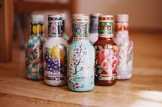 six colorful bottles are lined up on the table, with one empty bottle in the foreground