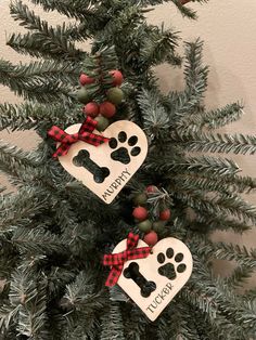 two wooden heart shaped ornaments hanging from a christmas tree with dog paw prints on them