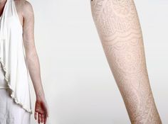 a woman in white is standing next to a leg with tattoos on it and her arm