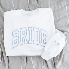 the bride sweatshirt and matching hat are laid out on a bed with grey linens