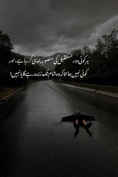 a person laying on the side of a road under a dark sky with an overcast sky