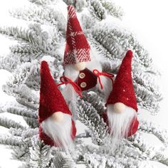 three red and white gnomes sitting on top of a pine tree