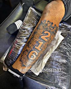 a man with a tattoo on his arm and leg sitting in a chair next to some foil