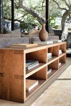 a living room filled with furniture and a vase on top of a book shelf next to a window