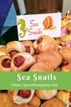 there are many small hot dogs on the table with sea snails in them and a sign that says sea snails