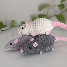 three crocheted mice sitting on top of each other in front of green leaves