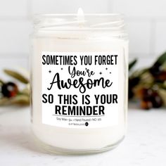 a white candle that says sometimes you forget your awesome someone so this is your reminder