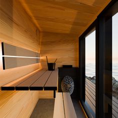 the inside of a sauna house with wooden walls and floor to ceiling windows looking out onto the ocean