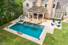 an aerial view of a house with a pool in the yard and chairs around it