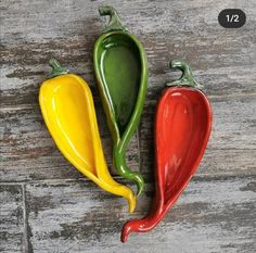 three different colored peppers sitting on top of a wooden table next to eachother