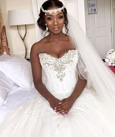 a woman in a wedding dress sitting on a bed wearing a tiara and veil