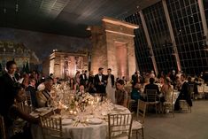 a group of people standing around a table with white clothed tables in front of them