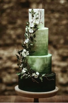 a green and black wedding cake with white flowers