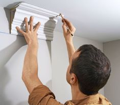 a man is working on an electrical fixture in the room with white walls and ceiling