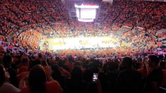 an orange and black basketball game is being played in a stadium with people watching from the stands