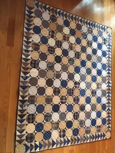 an old quilt is on the floor in front of a wooden wall with wood floors