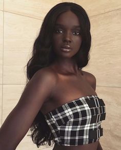 a woman in a black and white checkered top poses for the camera with her hands on her hips