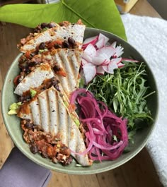 a bowl filled with different types of food on top of a wooden table next to a green leafy plant