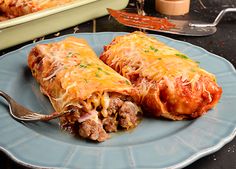 two enchiladas sitting on a plate with a fork in front of them