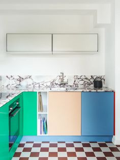 a kitchen with multicolored cabinets and checkered flooring