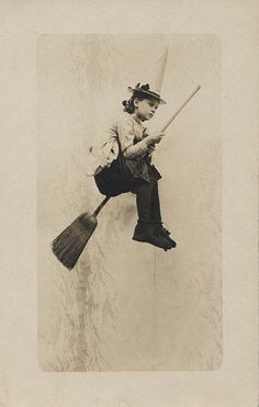 an old photo of a woman holding a broom and wearing a top hat while jumping in the air