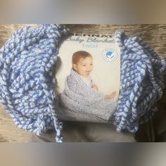 a blue and white crochet baby blanket sitting on top of a wooden table