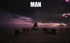 a pier with the words man on it in front of a dark sky and clouds